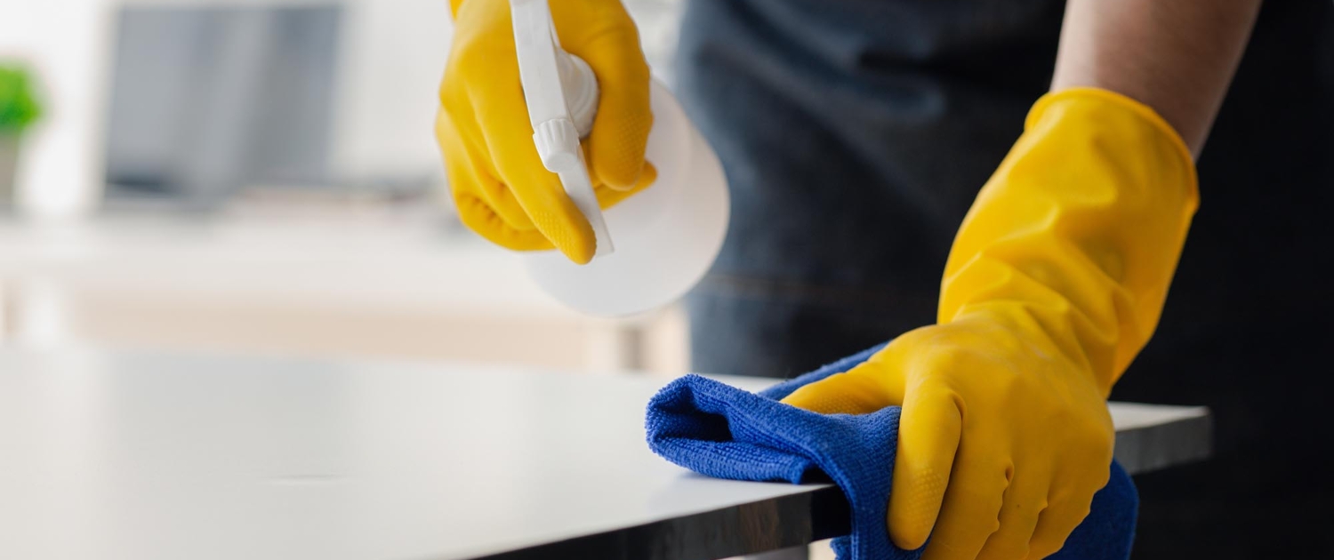 Front view of a person in yellow gloves sanitizing a surface