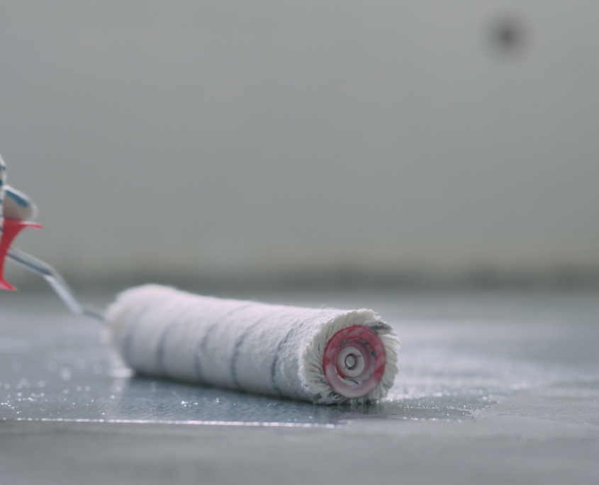 Side view of a roller applying a coating onto concrete floor