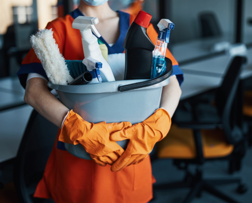 Front view of a cleaning worker holding a bucket of cleaning supplies