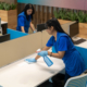 Side view of two professional cleaners wiping down surfaces in office space