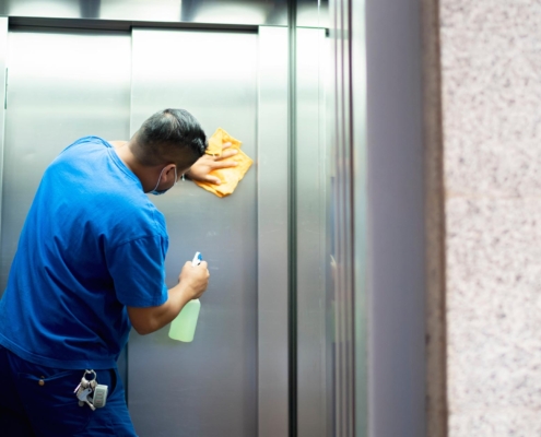 Janitor disinfecting office building elevator