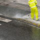 Worker cleaning the sidewalk with pressurized water. Maintenance or cleaning concept