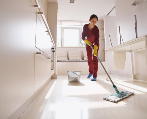 Concentrated uniformed professional janitor doing wet cleaning