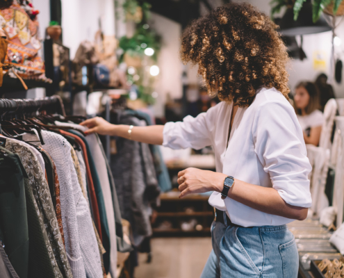 Side view of woman with curly hair looking at clothes at retail store