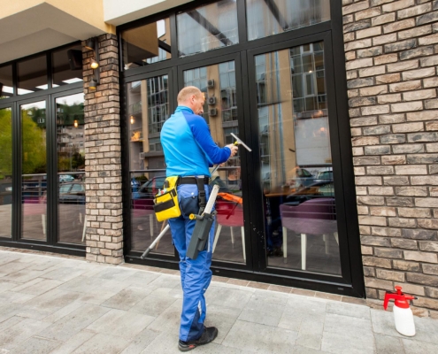 Worker cleaning windows outside business