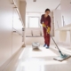 Concentrated uniformed professional janitor doing wet cleaning