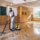 Side view of a man cleaning the floors of an empty classroom